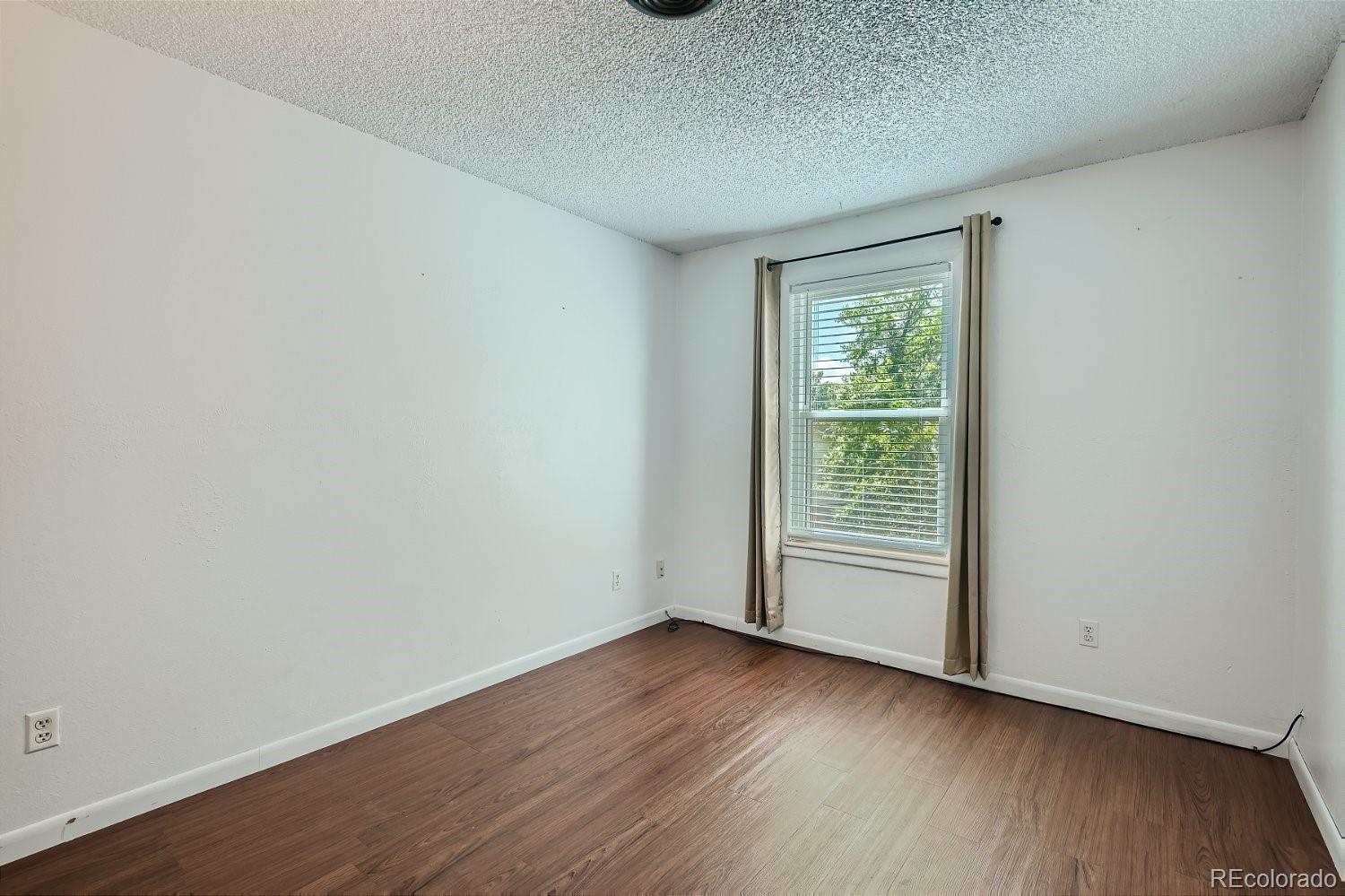 11099 Fairfax Circle Thornton, CO 80233 - Photo 24 of 33 a view of an empty room with wooden floor and a window