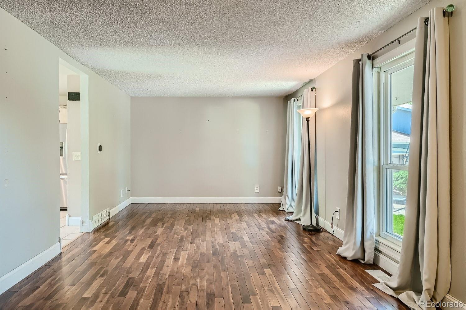 11099 Fairfax Circle Thornton, CO 80233 - Photo 8 of 33 an empty room with wooden floor and a glass door