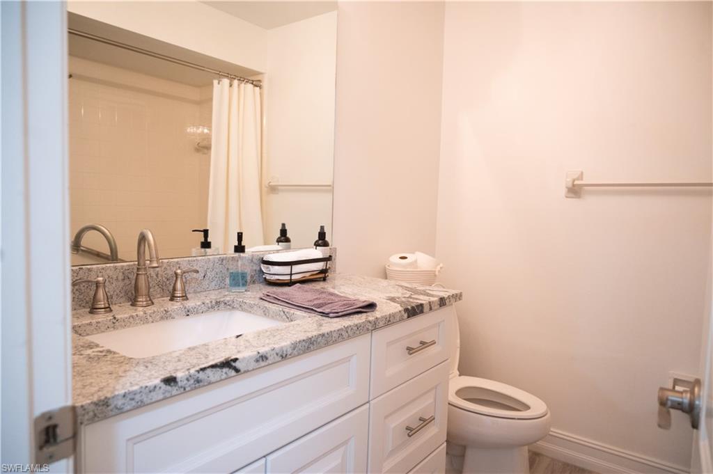 136 Harrison Road, Unit L3 Naples, FL 34112 - Photo 31 of 50 a bathroom with a granite countertop sink a toilet and a mirror