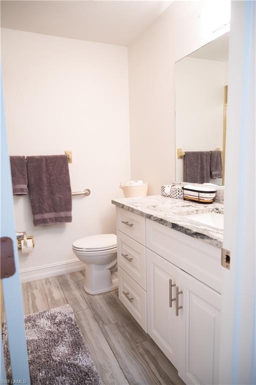 136 Harrison Road, Unit L3 Naples, FL 34112 - Photo 43 of 50 a bathroom with a granite countertop toilet a sink and a mirror