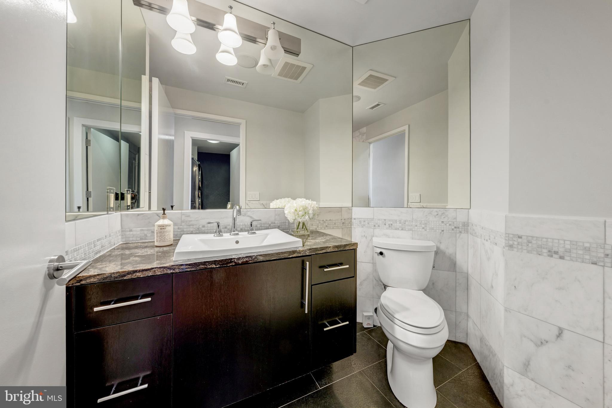 11990 Market Street, Unit 2112 Reston, VA 20190 - Photo 31 of 92 a bathroom with a granite countertop toilet sink and mirror