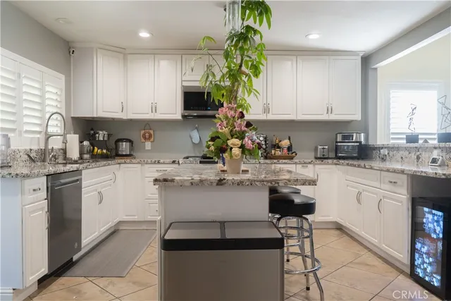 a kitchen with kitchen island granite countertop white cabinets sink and stainless steel appliances
