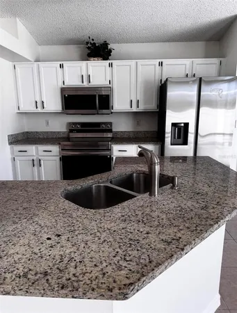 a kitchen with kitchen island granite countertop a sink and a stove