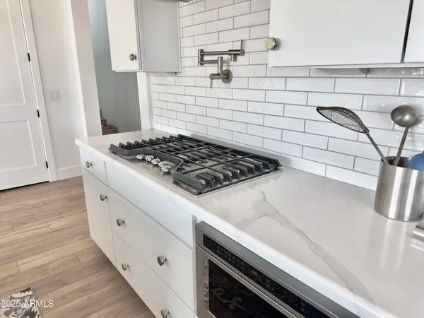 a living room with stainless steel appliances furniture and a wooden floor