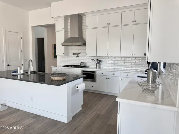 a kitchen with granite countertop a stove and white cabinets