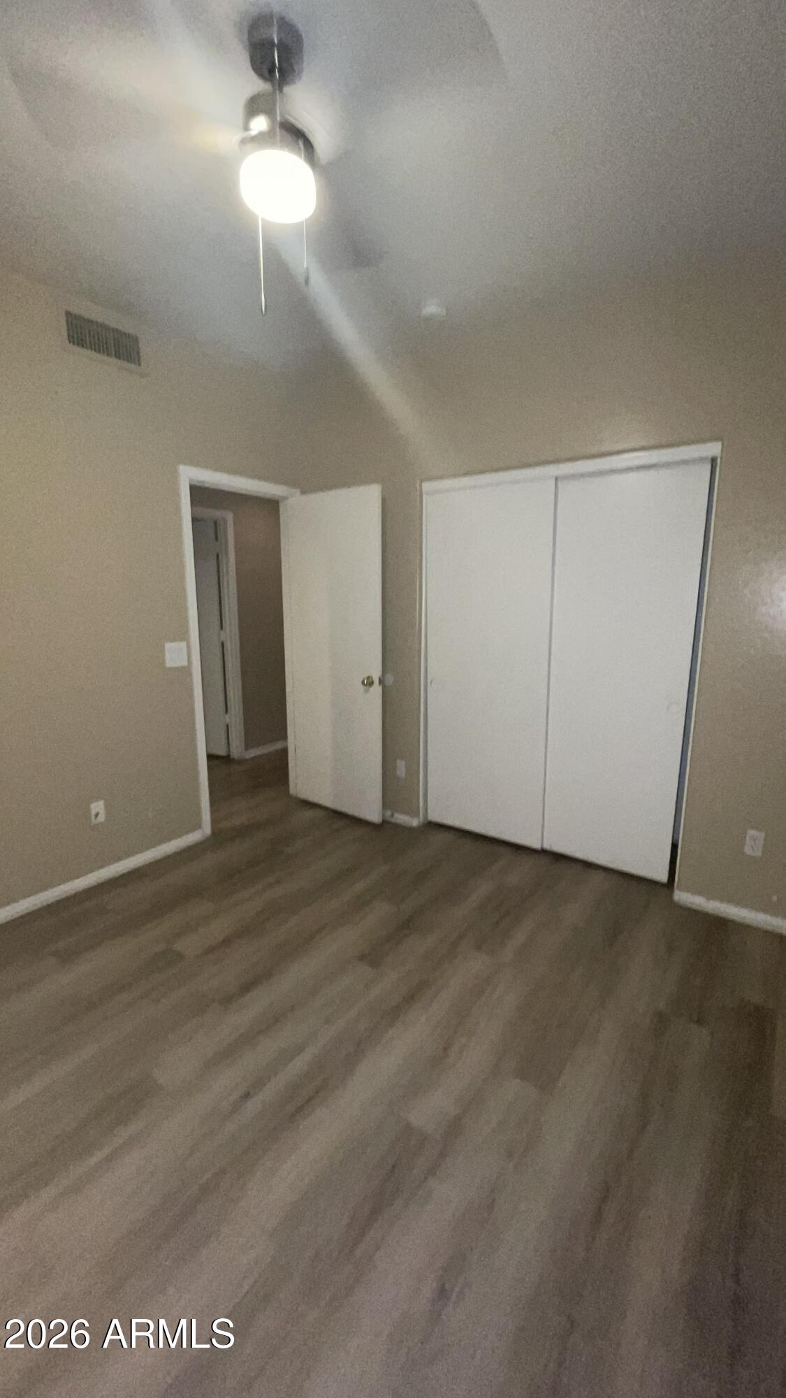 10640 West Coronado Road Avondale, AZ 85392 - Photo 18 of 26 an empty room with wooden floor chandelier fan and windows