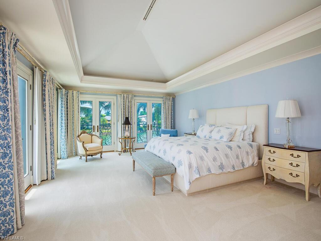 3580 Gin Lane Naples, FL 34102 - Photo 36 of 38 a spacious bedroom with a bed and a couch next to a window