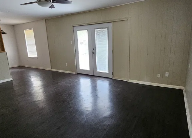 an empty room with wooden floor and windows