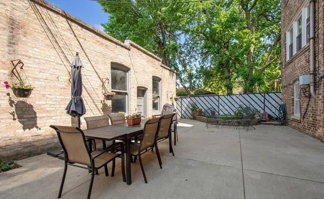 a view of a patio with a table and chairs and wooden fence