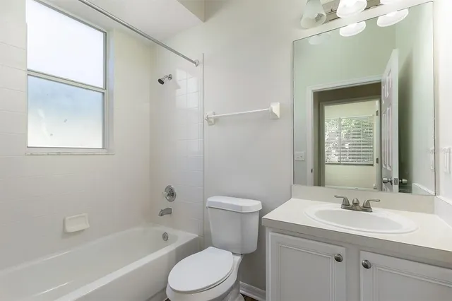 a bathroom with a toilet a sink a mirror a bathtub and vanity