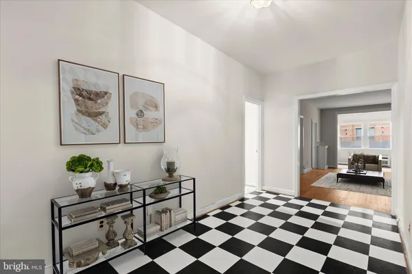 a living room with a black white checkered floor with a gaming machine and dining chairs