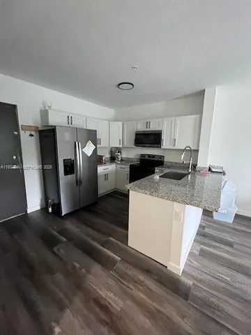 a kitchen with stainless steel appliances kitchen island granite countertop a refrigerator a stove top oven a sink and dishwasher