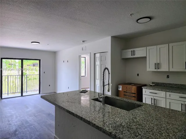 a kitchen with granite countertop a sink a stove and cabinets