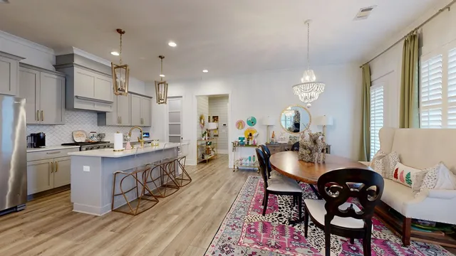 a kitchen with stainless steel appliances granite countertop a stove a sink dishwasher a dining table and chairs with wooden floor