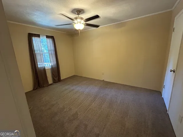 an empty room with a window and a fan