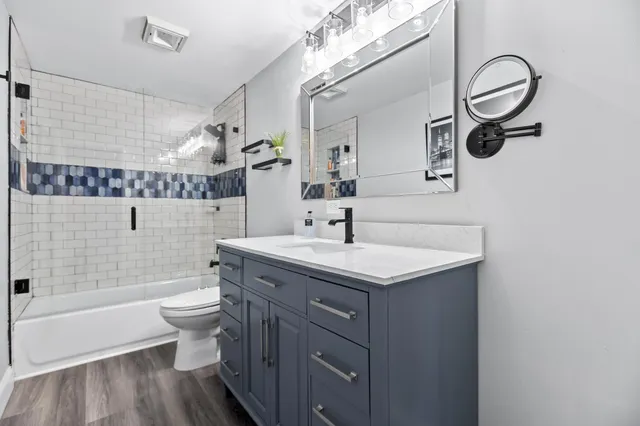 a bathroom with a granite countertop sink a toilet and shower