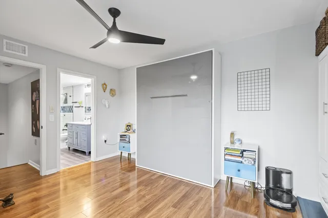 a view of empty room with wooden floor and fan