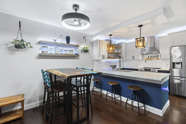 a kitchen with stainless steel appliances a dining table chairs and wooden floor