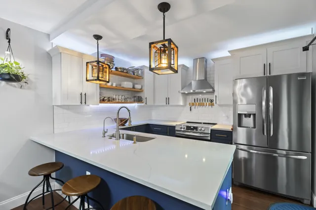 a kitchen with stainless steel appliances a sink a refrigerator a stove and white cabinets