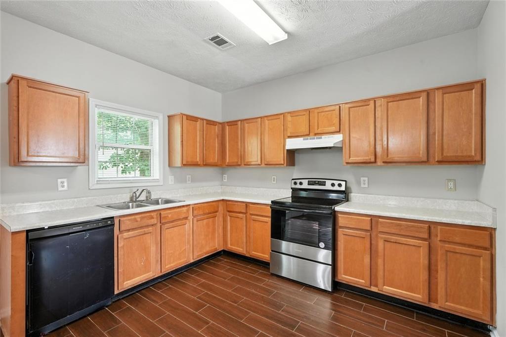 5487 Walnut Lane Lithonia, GA 30038 - Photo 11 of 43 a kitchen with stainless steel appliances granite countertop wooden cabinets a sink and dishwasher a stove with wooden floor