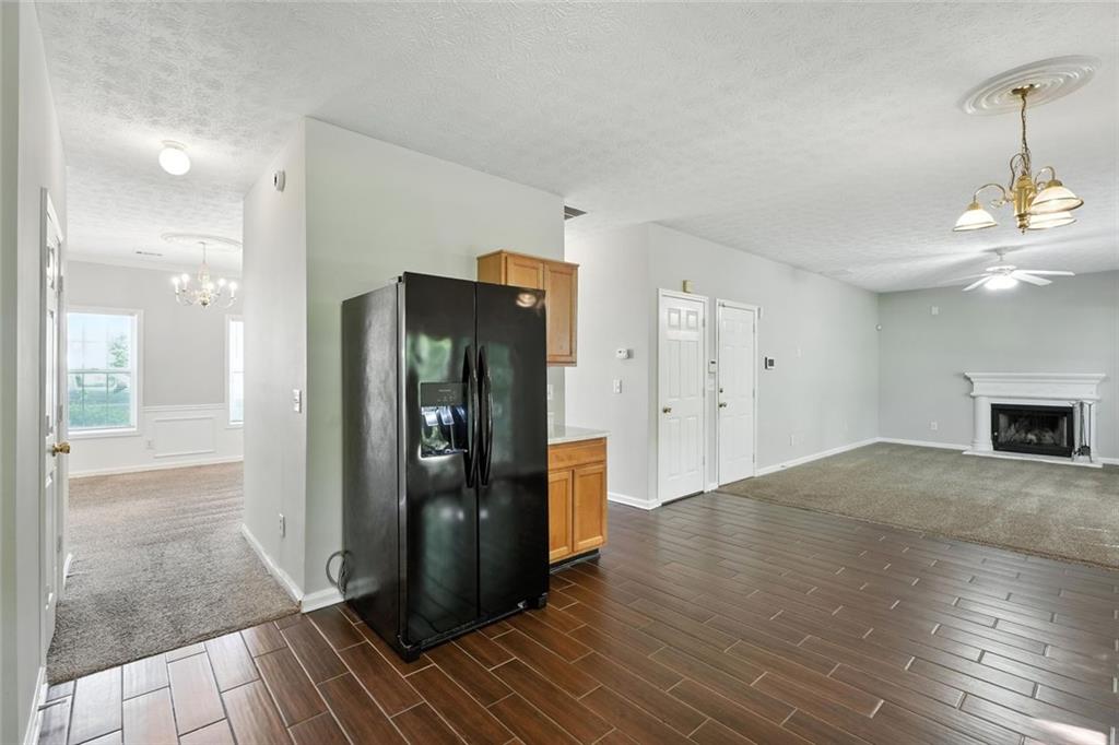5487 Walnut Lane Lithonia, GA 30038 - Photo 13 of 43 a view of a refrigerator in kitchen and an empty room with wooden floor
