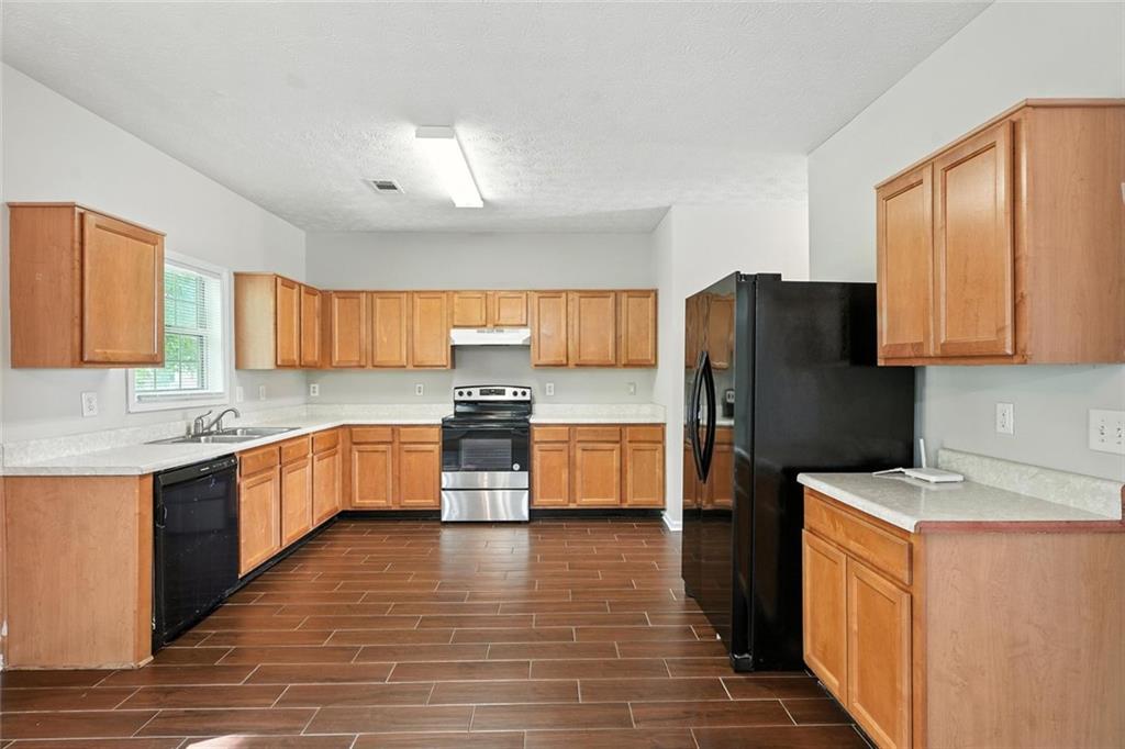 5487 Walnut Lane Lithonia, GA 30038 - Photo 10 of 43 a kitchen with stainless steel appliances a refrigerator a sink a stove top oven a counter space and cabinets