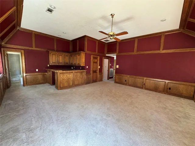 a view of an empty room with window and a kitchen