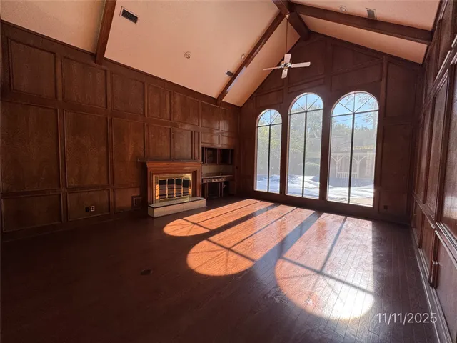 an empty room with wooden floor fan and a floor to ceiling window