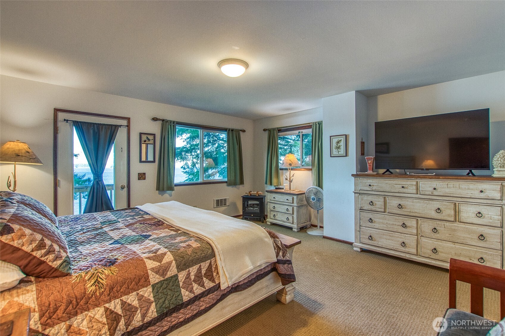 673 Raccoon Point Road Orcas Island, WA 98245 - Photo 29 of 40 a bedroom with a large bed and a flat screen tv on the dresser