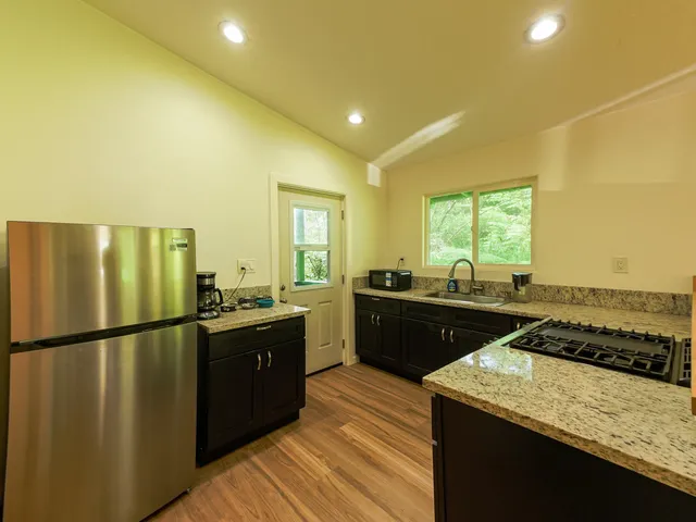 a kitchen with stainless steel appliances granite countertop sink stove and refrigerator