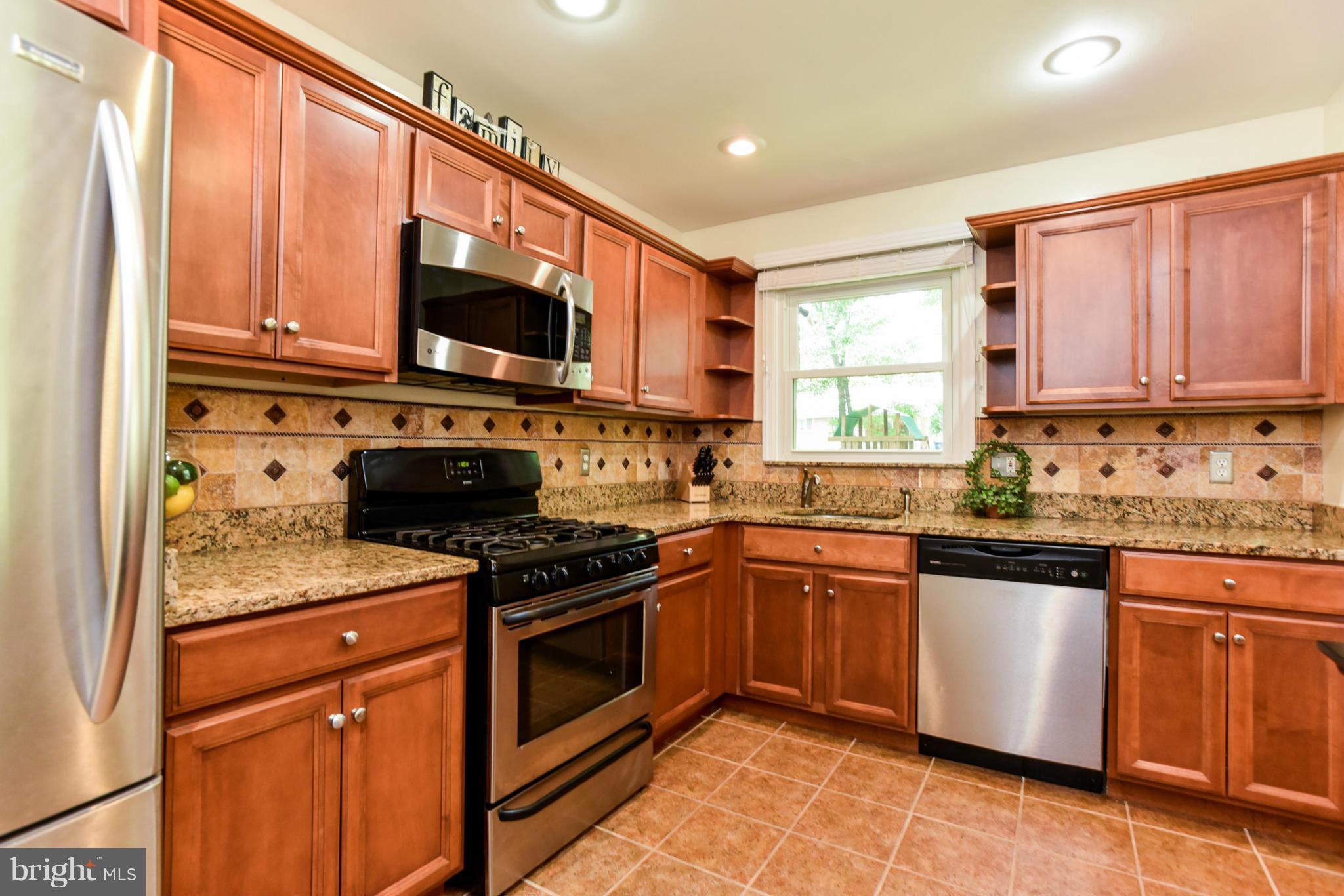 5614 Heming Avenue Springfield, VA 22151 - Photo 6 of 30 a kitchen with stainless steel appliances granite countertop a stove sink microwave and refrigerator