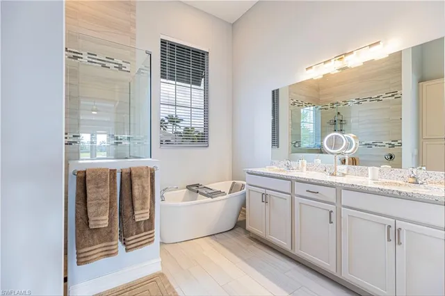 a spacious bathroom with a double vanity sink a mirror and a bathtub