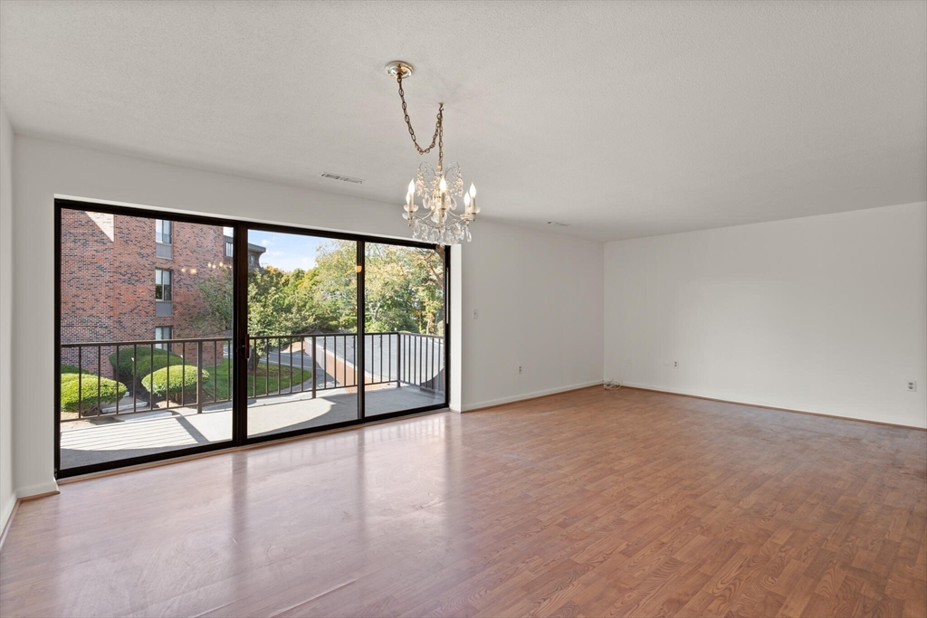 1008 Paradise Road, Unit 2R Swampscott, MA 01907 - Photo 9 of 18 a view of an empty room with wooden floor and a window