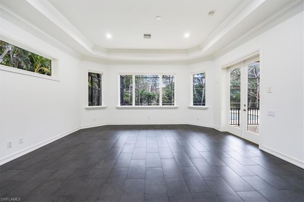3110 Crayton Road Naples, FL 34103 - Photo 15 of 38 Large primary bedroom with tile floors, windows/sliders for natural light and access to the pool/spa/lanai.