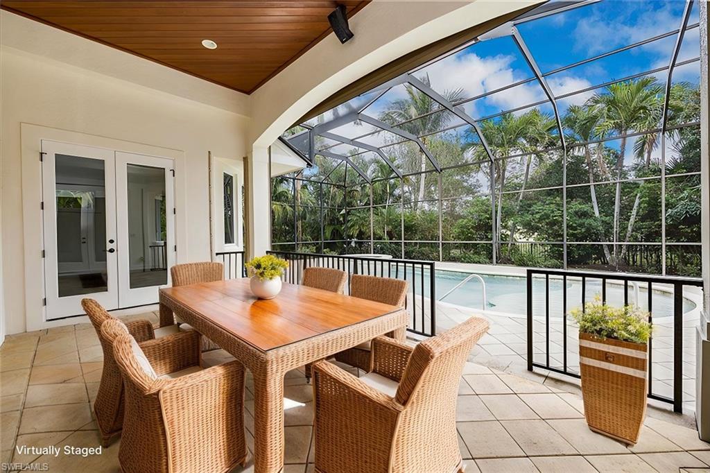3110 Crayton Road Naples, FL 34103 - Photo 29 of 38 Virtually Staged - Covered area with wood ceiling, pavers and french doors with views of the pool/spa/enclosed lanai.