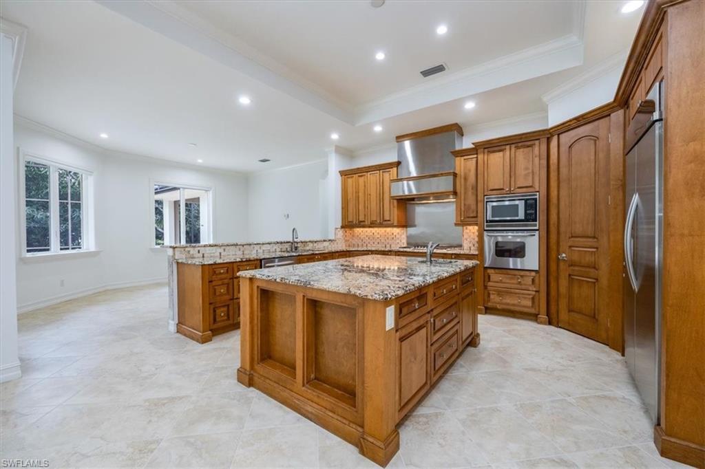 3110 Crayton Road Naples, FL 34103 - Photo 6 of 38 Kitchen with large center island, granite countertops with wood cabinetry and stainless steel appliances.
