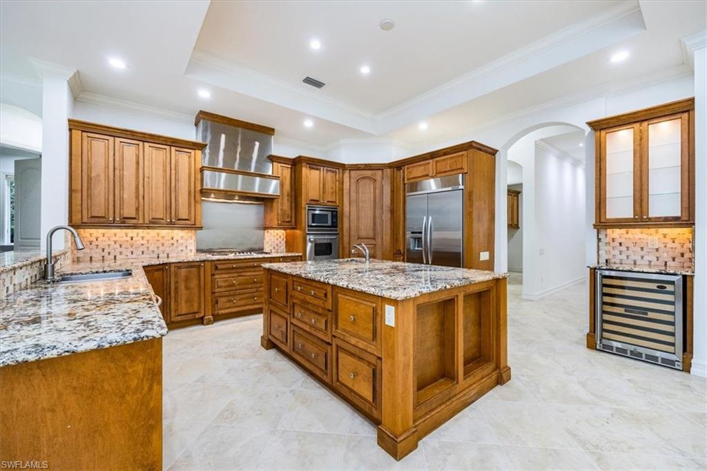 3110 Crayton Road Naples, FL 34103 - Photo 7 of 38 Kitchen with large center island, granite countertops with wood cabinetry and stainless steel appliances.