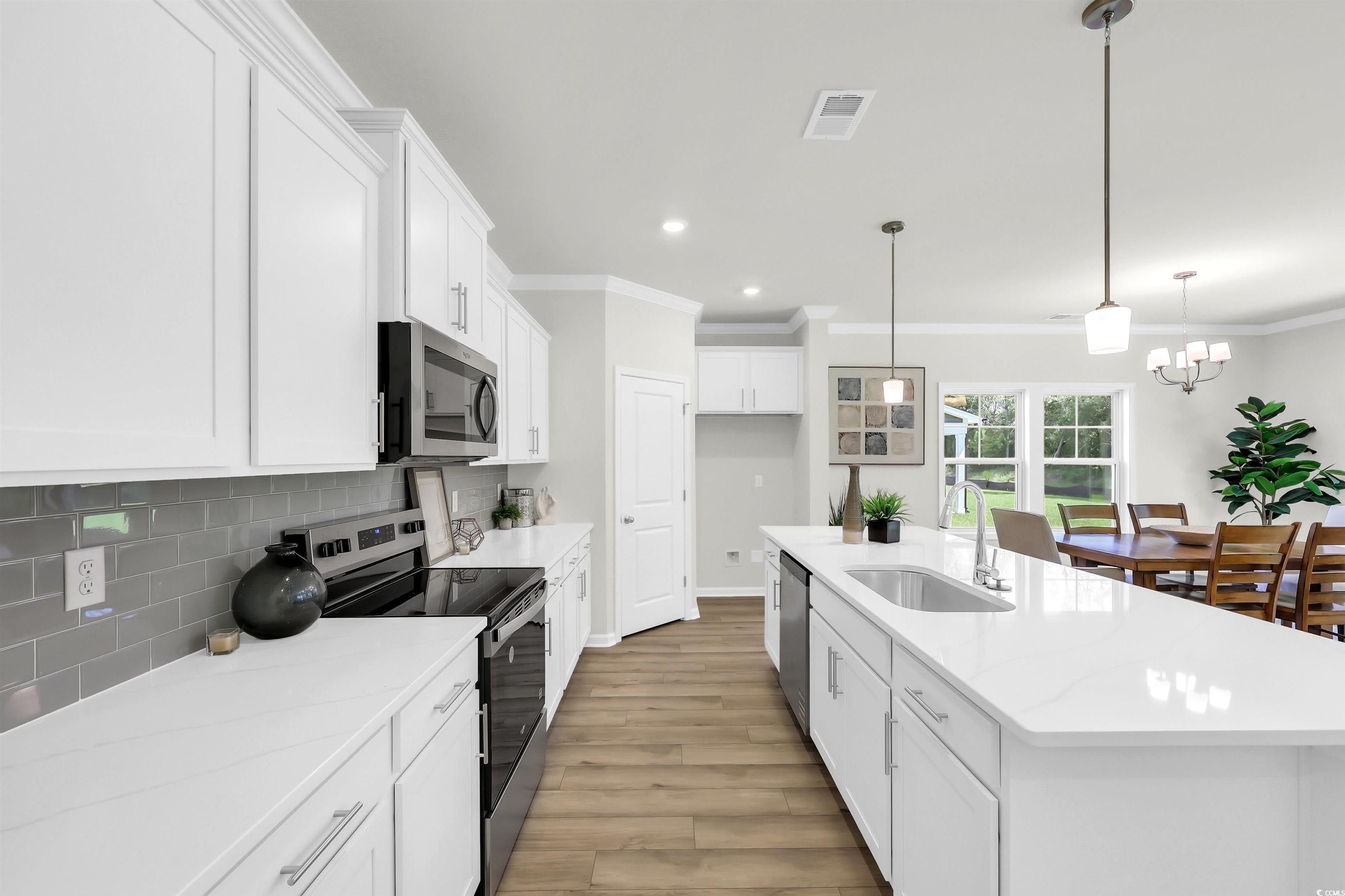 113 Cascade Drive Conway, SC 29527 - Photo 4 of 12 Kitchen featuring recessed lighting, a breakfast bar area, white cabinets, stainless steel appliances, and hanging light fixtures