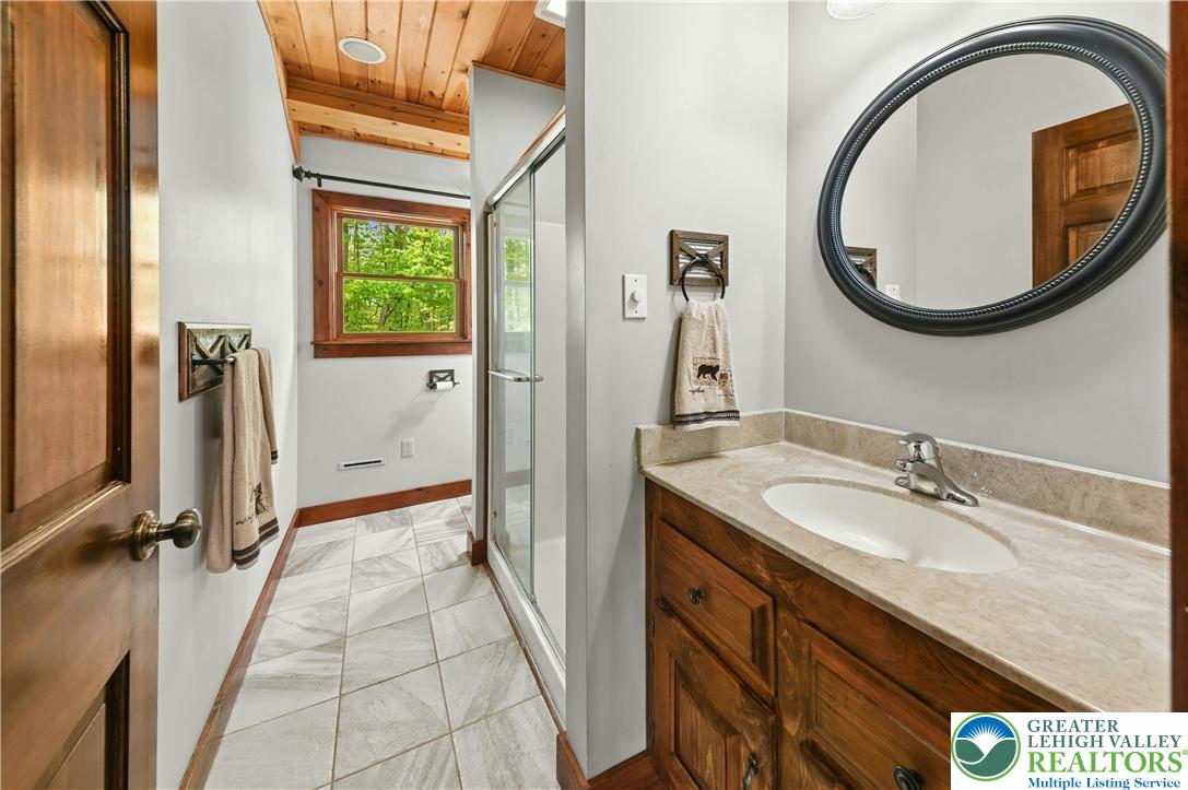 294 Nockamixon Road Kintnersville, PA 18930 - Photo 37 of 58 a bathroom with a granite countertop sink a mirror and a shower