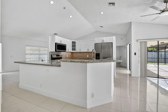 a kitchen with stainless steel appliances kitchen island granite countertop a refrigerator a stove a microwave oven a sink with island and chairs