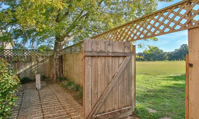 a view of a backyard with wooden fence and large trees