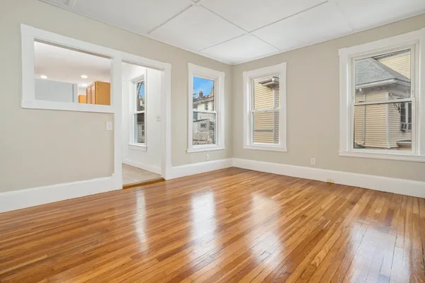 a view of an empty room with wooden floor and a window