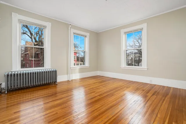 a view of an empty room with glass door and wooden floor