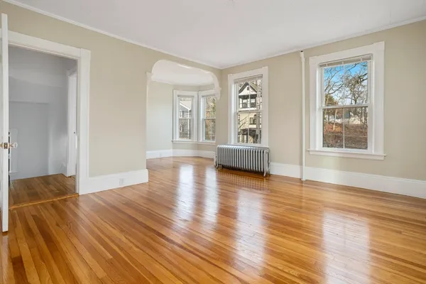 a view of an empty room with wooden floor and a window