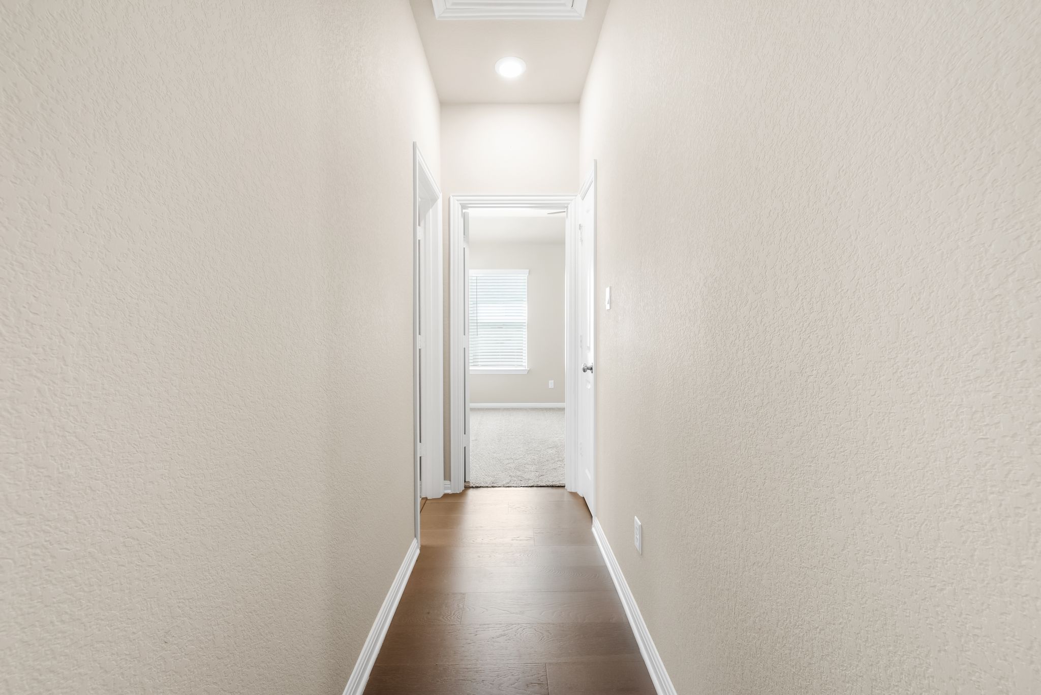300 Prato Place Georgetown, TX 78628 - Photo 26 of 40 A well-lit corridor featuring rich hardwood flooring extends to a distant room.