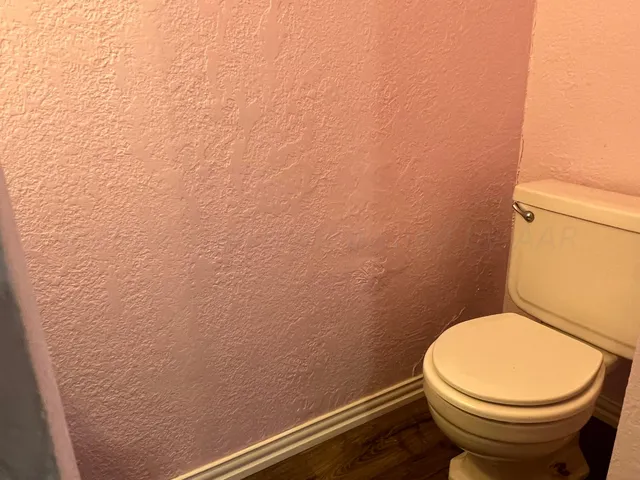 a white toilet sitting next to a white wall
