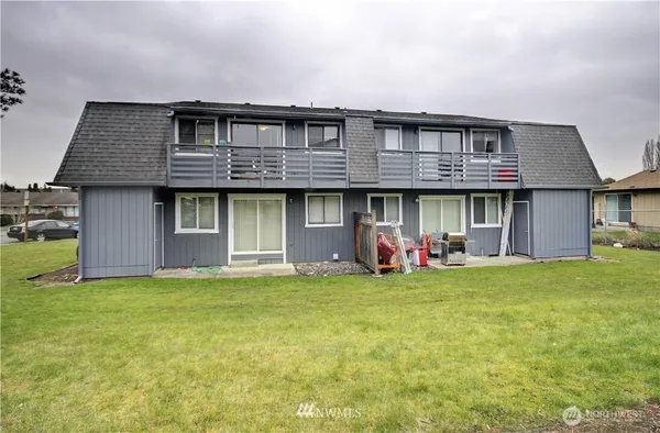 a view of a brick house with a big yard and large trees