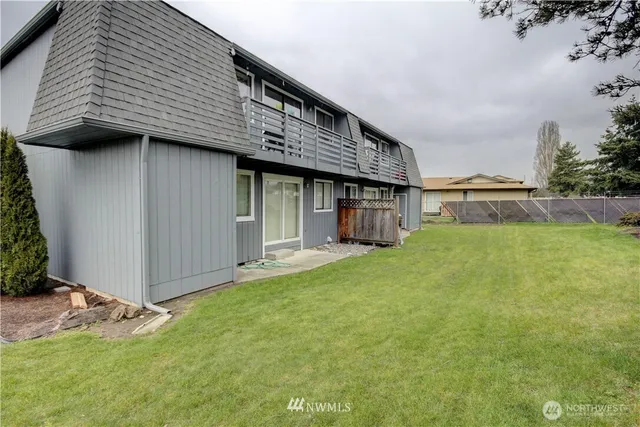 a view of a house with a yard plants and large tree