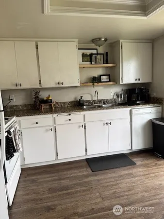 a kitchen with granite countertop a sink a stove and cabinets