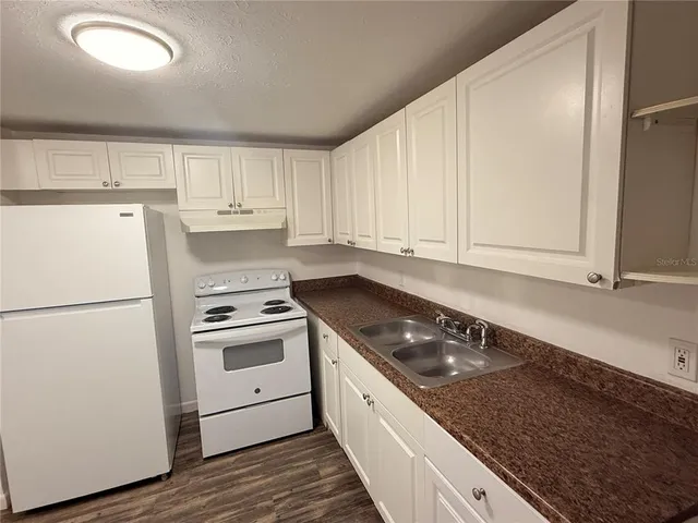 a kitchen with granite countertop white cabinets and white appliances
